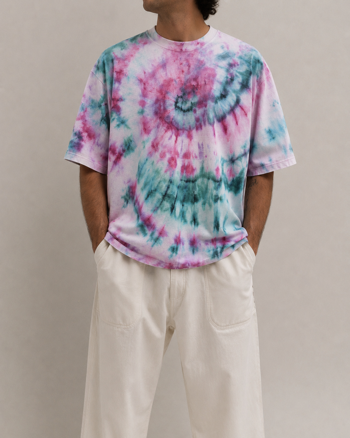 A person wearing a short-sleeve tie-dye t-shirt with pink and teal swirls, paired with off-white wide-leg pants, against a hemp plain beige studio background. Hemp Horizon
