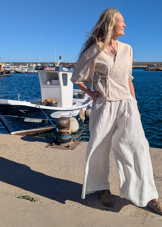Woman in a light outfit standing by a dock with boats in the background - Hemp Horizon