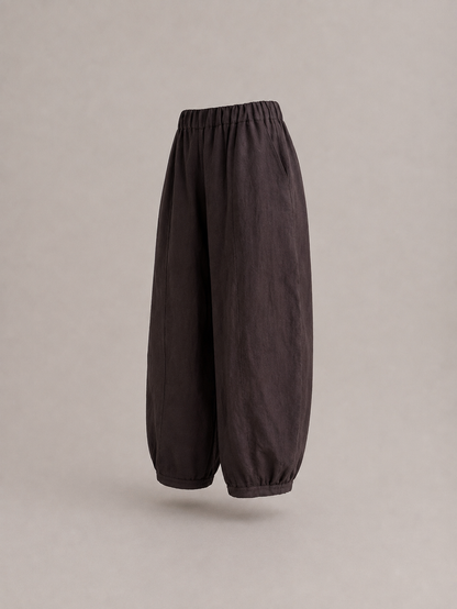 Dark brown baggy pants with an elastic waistband and gathered cuffs, shown floating against a neutral gray background. emp Horizon
