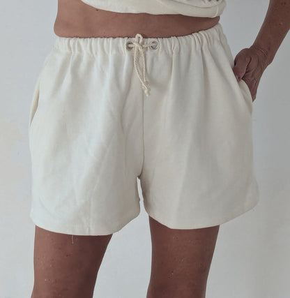 Person wearing beige shorts on a plain background