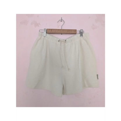 Beige shorts on a hanger against a pink background